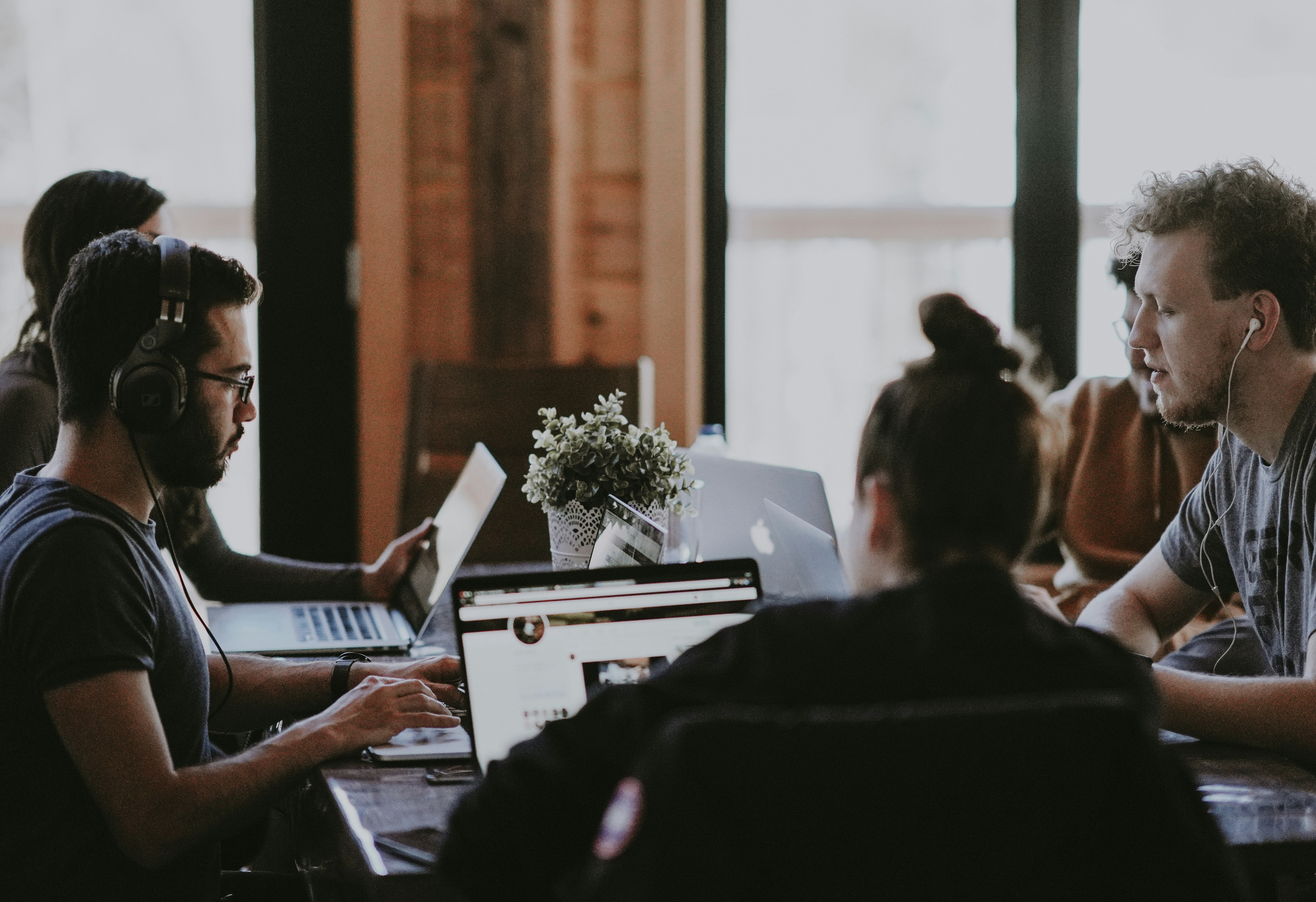 Junges Team arbeitet gemeinsam an Laptops in offenem Workspace – Fokus auf digitale Zusammenarbeit und Kommunikation.